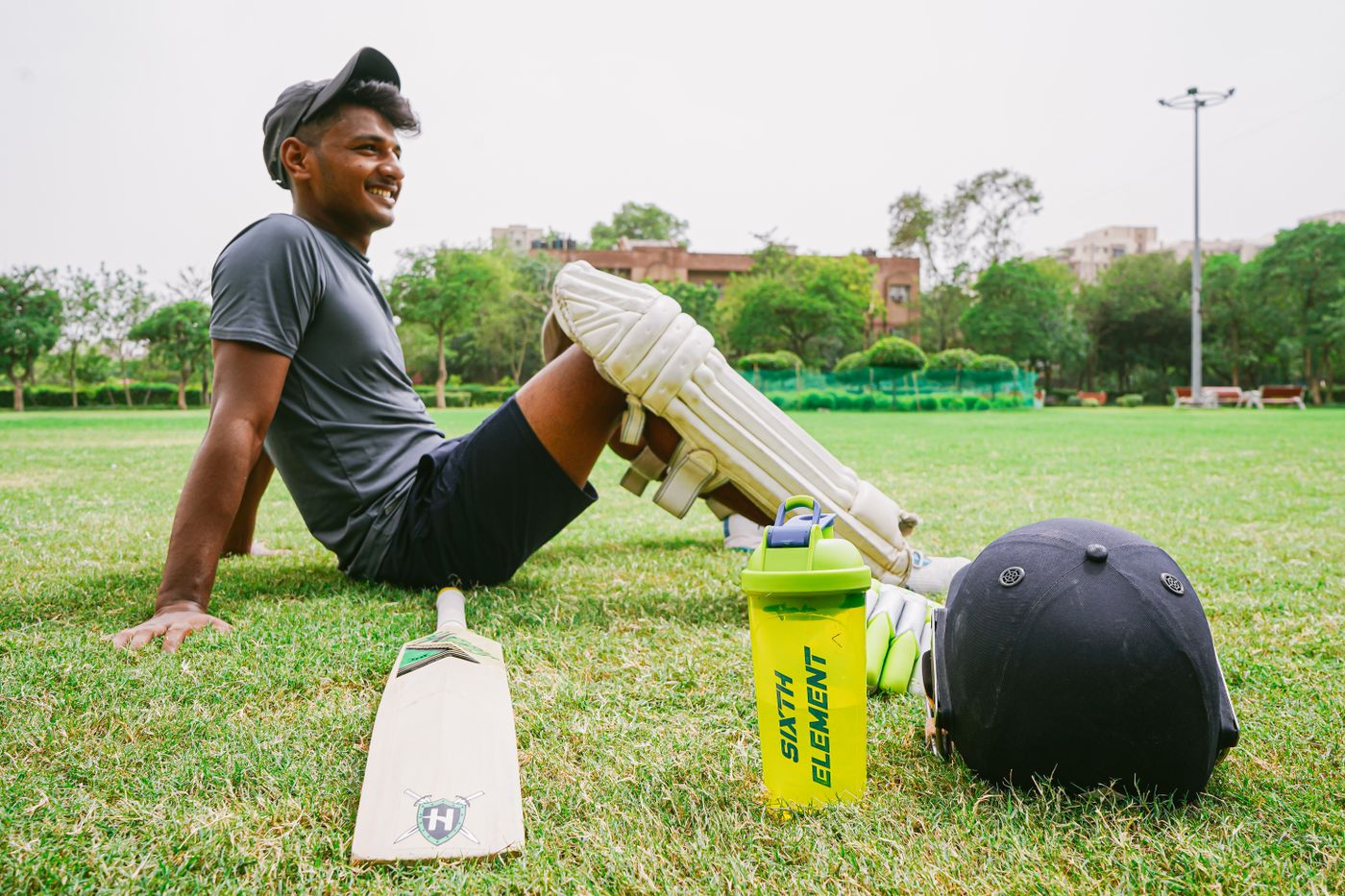 Cricketer resting beside bat helmet and pads